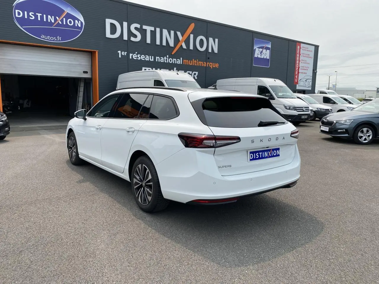 Vue 3/4 arrière droite d'une Skoda Superb Combi blanche pure avec vitres surteintées et jantes alliage noires polies.