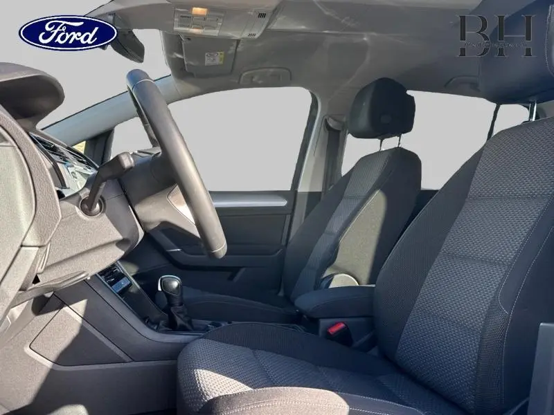 Vue intérieure côté conducteur du Volkswagen Touran 2.0 TDI 150ch Life Plus avec sièges tissu noir et volant multifonction.