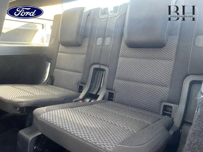 Vue rapprochée des sièges arrière en tissu noir avec appuie-têtes, montrant la troisième rangée d'un véhicule.