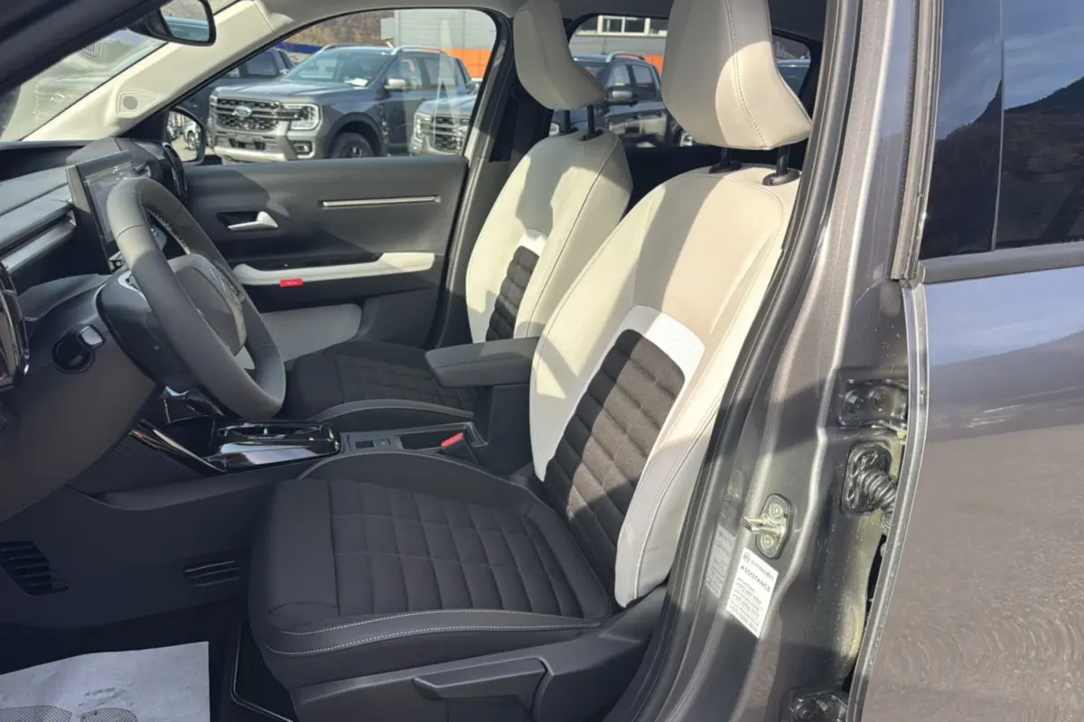 Vue intérieure côté gauche du Citroën C3 Aircross gris mercury avec sièges tissu bicolores et accoudoir central.