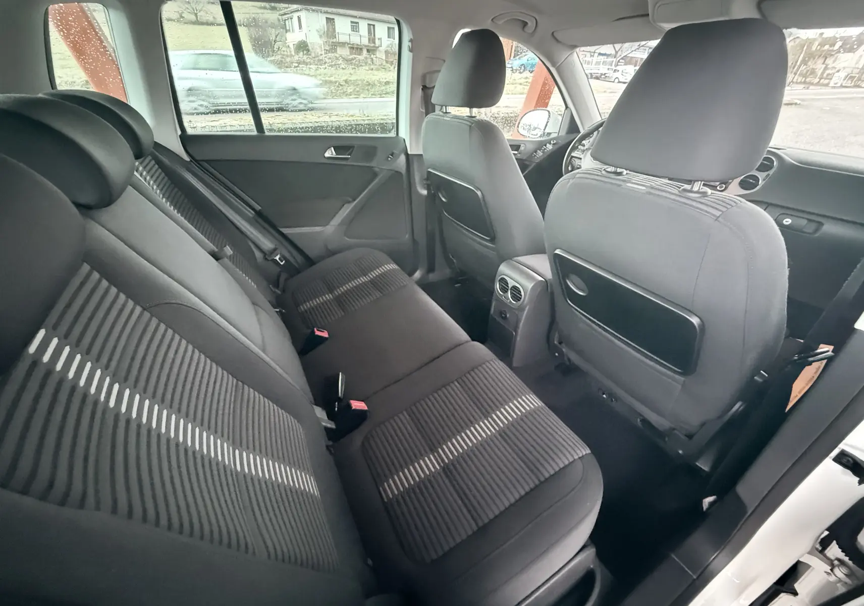 Vue intérieure arrière côté gauche du Volkswagen Tiguan 2.0 TDI 140 de 2010 avec sièges tissu noir et détails rayés.