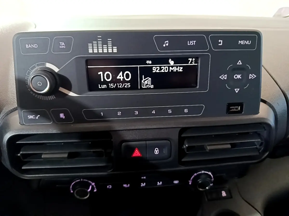 Vue rapprochée du tableau de bord noir du Citroën Berlingo XL blanc, affichant l’horloge et la radio digitale.