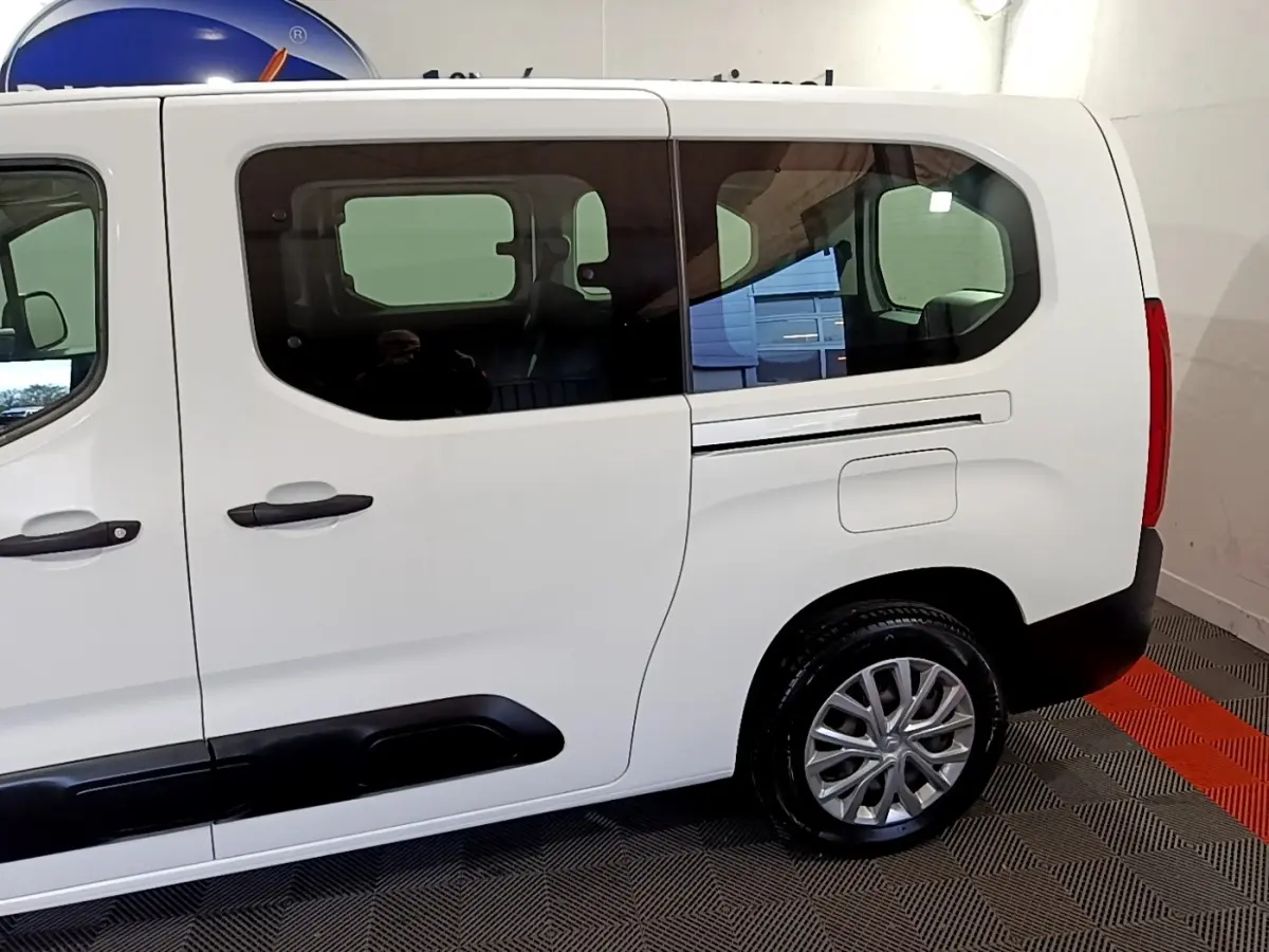 Vue latérale droite d'un Citroën Berlingo XL blanc, mettant en valeur les grandes fenêtres teintées et les protections noires sur les portières.