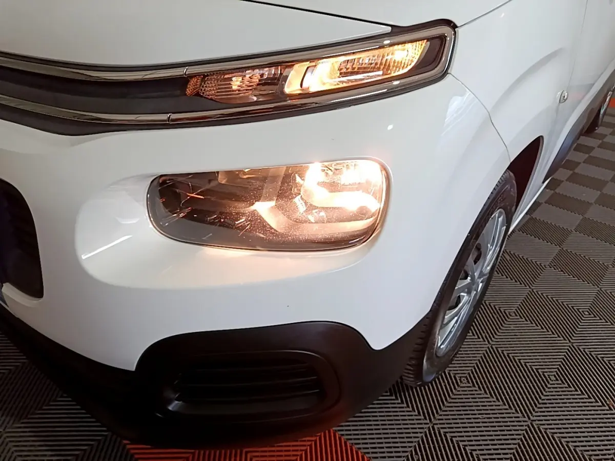 Gros plan sur l'avant droit blanc du Citroën Berlingo 2019 avec phares allumés et pare-chocs noir.