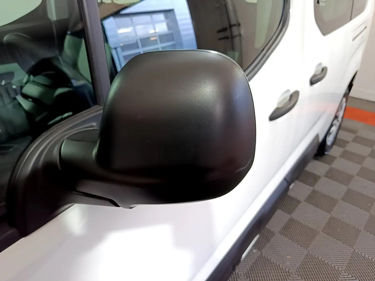 Rétroviseur noir en gros plan côté gauche d’un Citroën Berlingo blanc XL, vue partielle avant droite.
