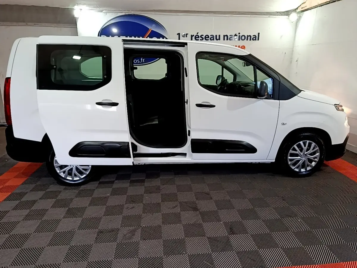 Vue de profil droit d'un Citroën Berlingo XL blanc 2019 avec porte coulissante arrière ouverte en intérieur showroom.