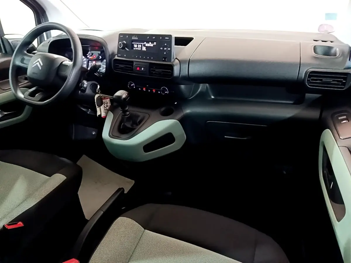 Vue intérieure côté conducteur du tableau de bord noir et gris du Citroën Berlingo XL 2019 avec volant et levier de vitesses manuelle.