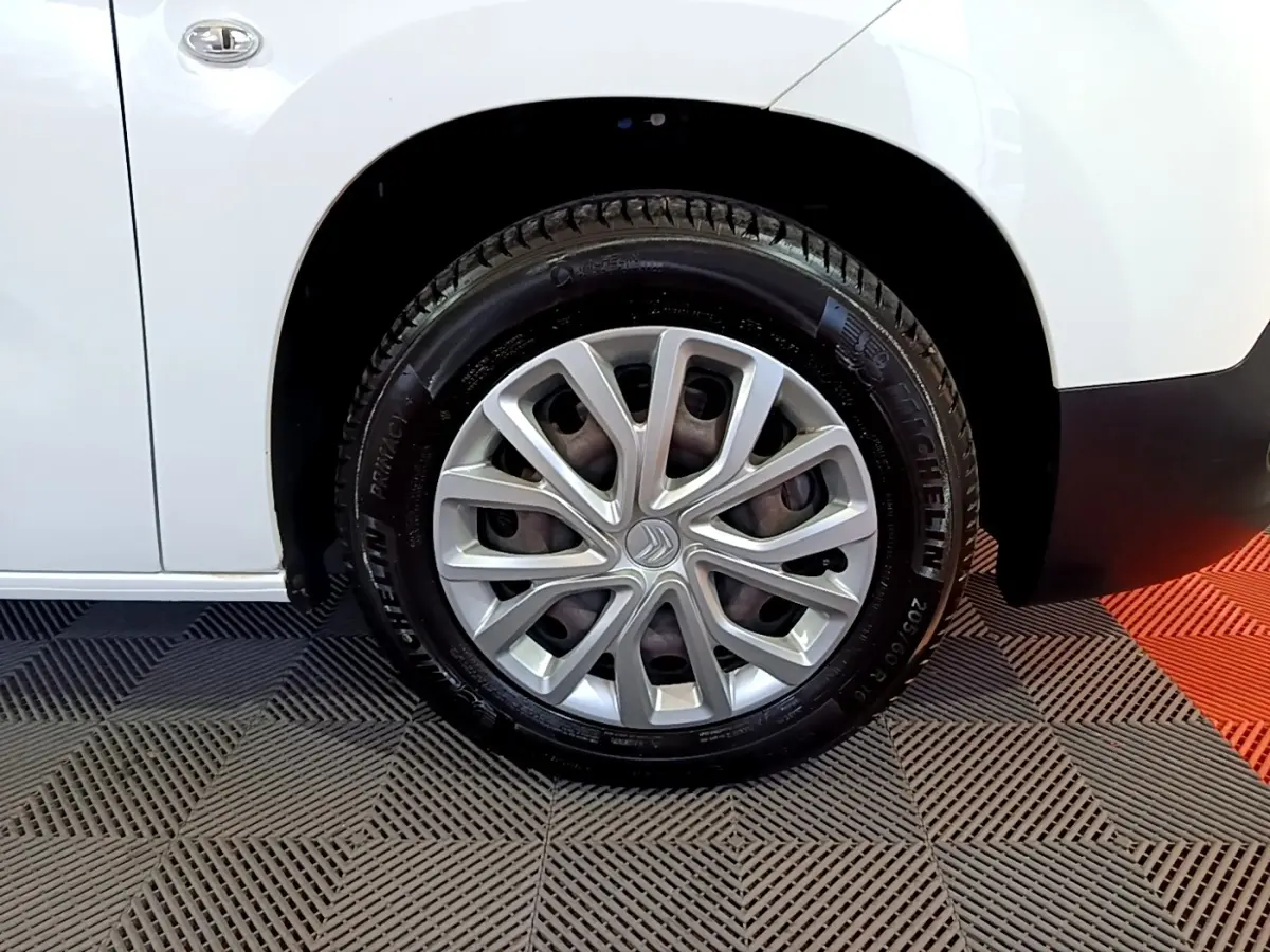 Gros plan sur la roue avant gauche blanche d’un Citroën Berlingo XL 2019 avec jante argentée et logo Citroën central.