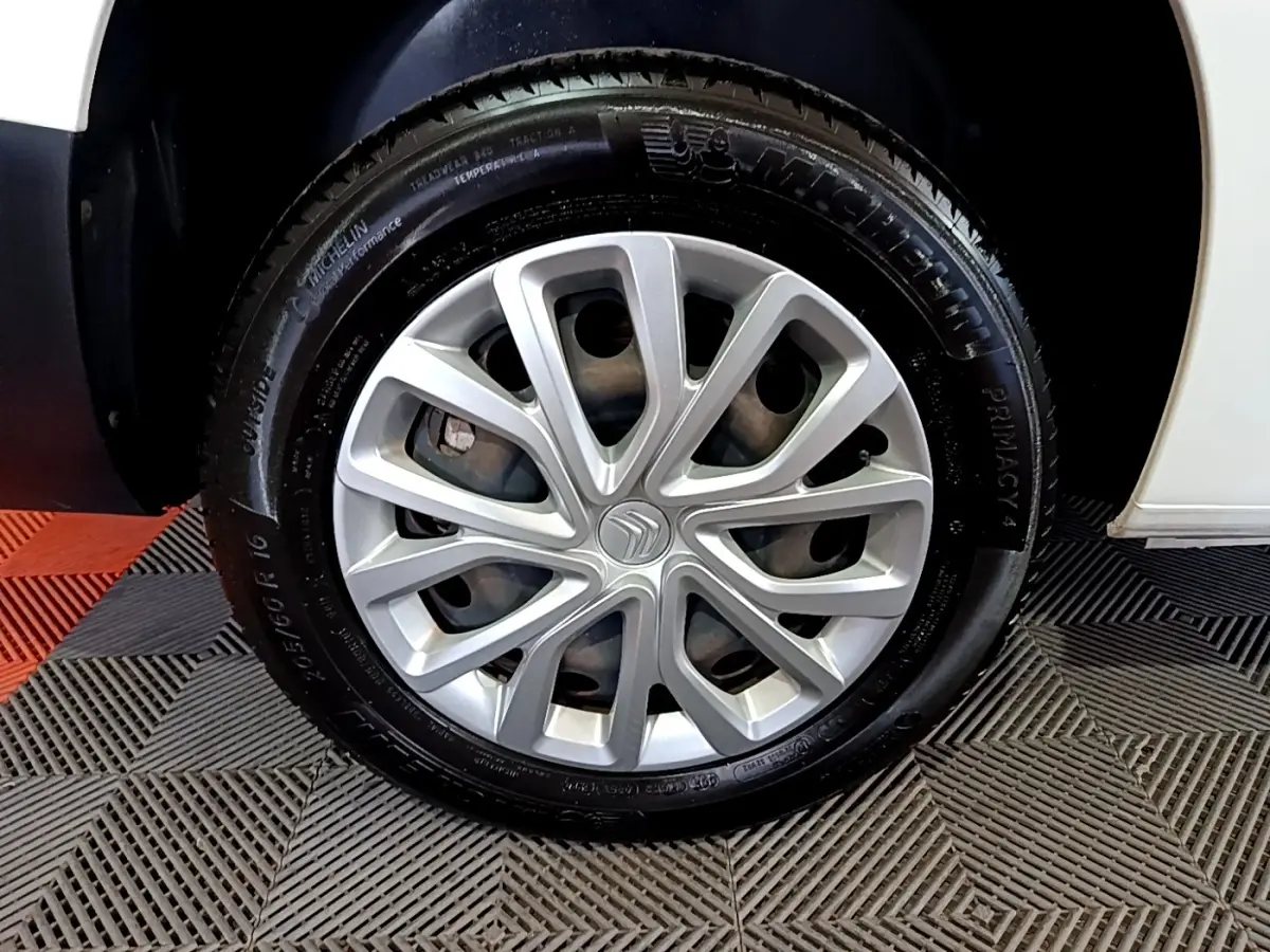 Gros plan sur la roue avant droite avec jante argentée et pneu Michelin du Citroën Berlingo blanc 2019.