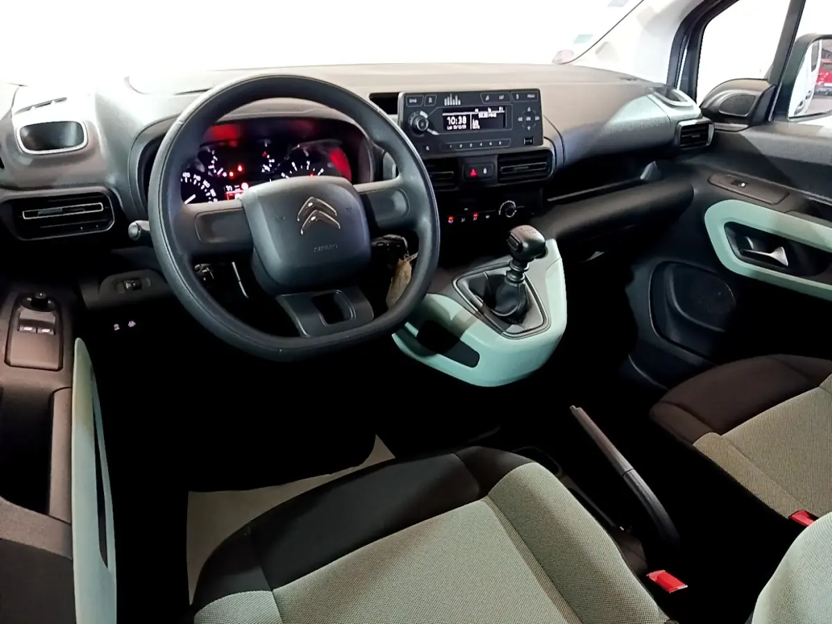 Vue intérieure côté conducteur du Citroën Berlingo blanc, avec volant, tableau de bord et levier de vitesses manuelle visibles.