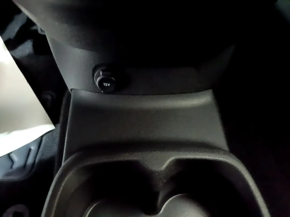 Prise 12V et porte-gobelets en gros plan dans l’habitacle sombre d’un Citroën Berlingo XL blanc.