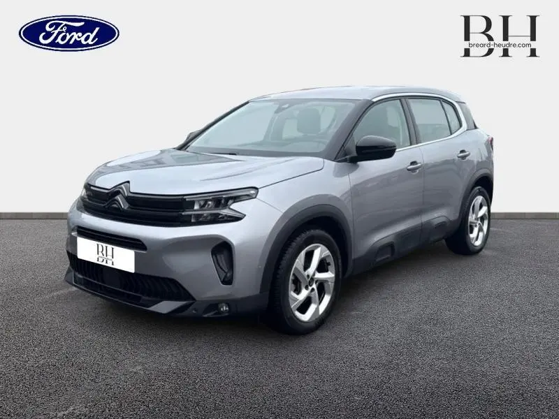 Citroën C5 Aircross gris acier en 3/4 avant droit, avec jantes alu et détails noirs brillants sur carrosserie.