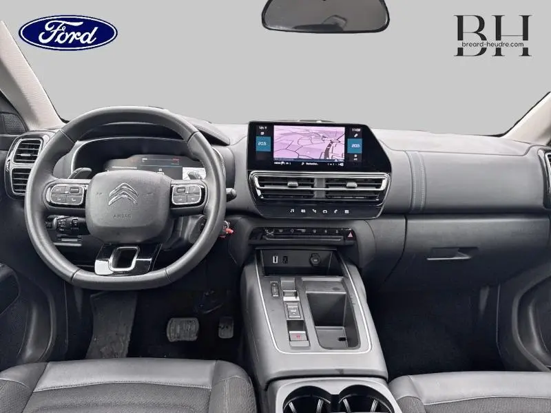 Vue intérieure avant du poste de conduite du Citroën C5 Aircross 2023 avec volant cuir multifonction et écran tactile central.