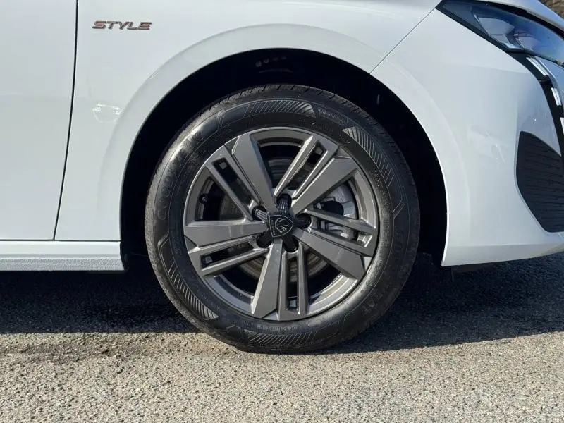 Gros plan sur la roue avant droite et l'aile blanche Okénite d'une Peugeot 308 Style avec jante alu et badge Style visible.