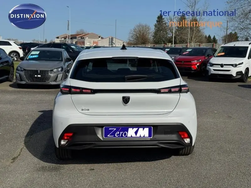 Vue arrière d'une Peugeot 308 blanche Okénite avec feux arrière LED et logo noir au centre du hayon.
