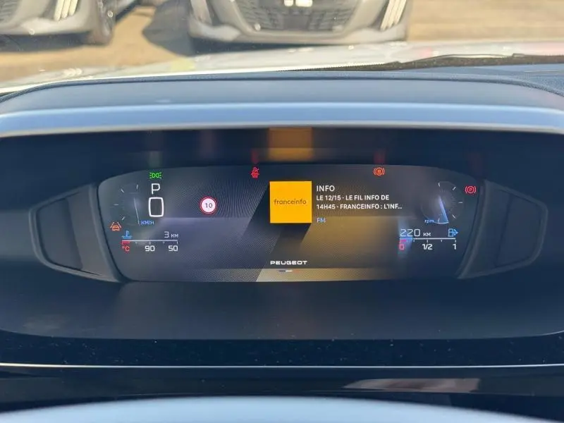 Vue rapprochée du tableau de bord numérique de la Peugeot 308 blanc Okénite, affichant infos et vitesse digitale.