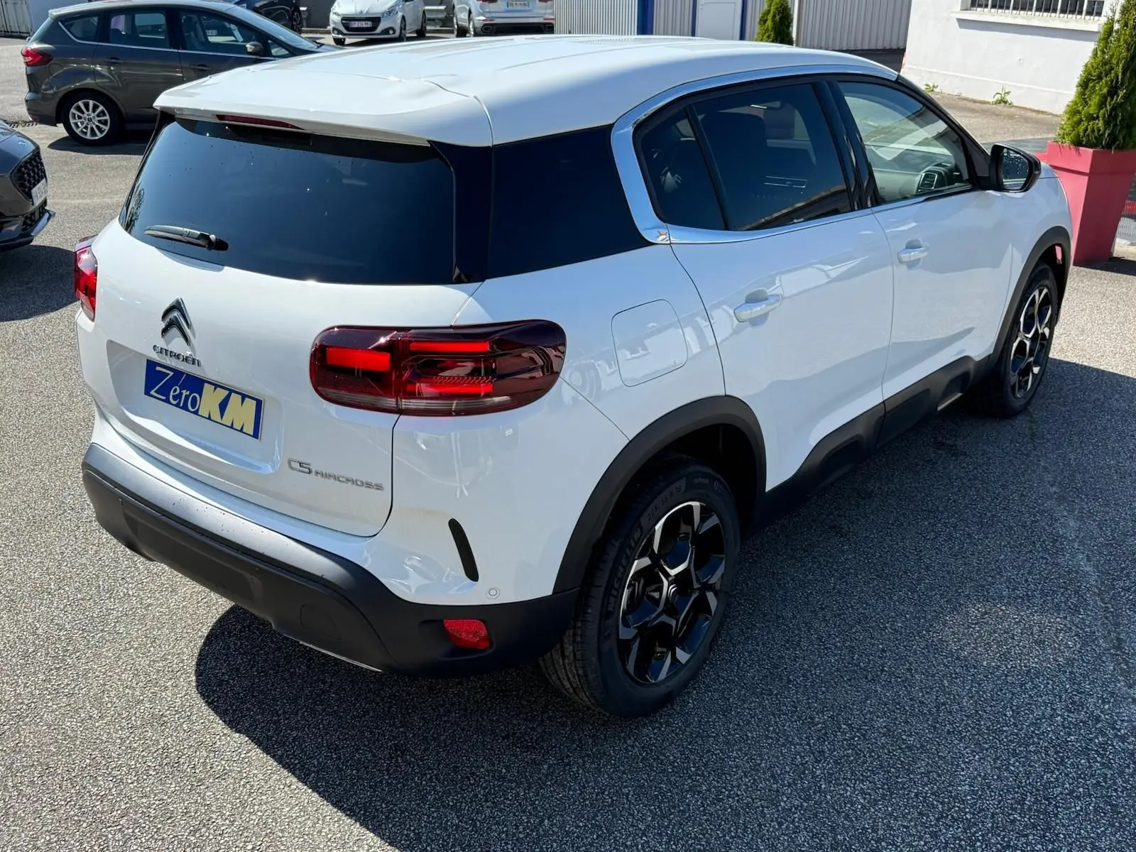 Vue 3/4 arrière droite du Citroën C5 Aircross blanc banquise avec toit noir et jantes bi-ton distinctives.