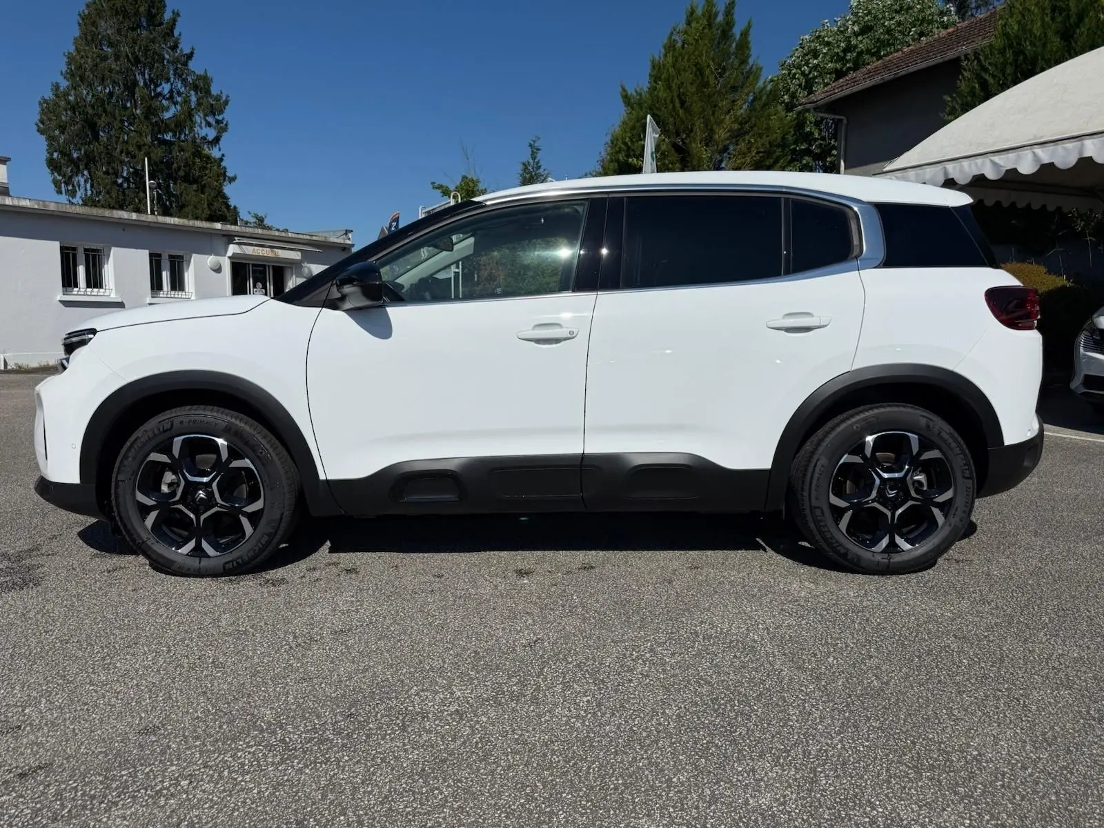 Profil côté gauche d'un Citroën C5 Aircross blanc Banquise avec protections noires sur les bas de caisse et arches de roues.