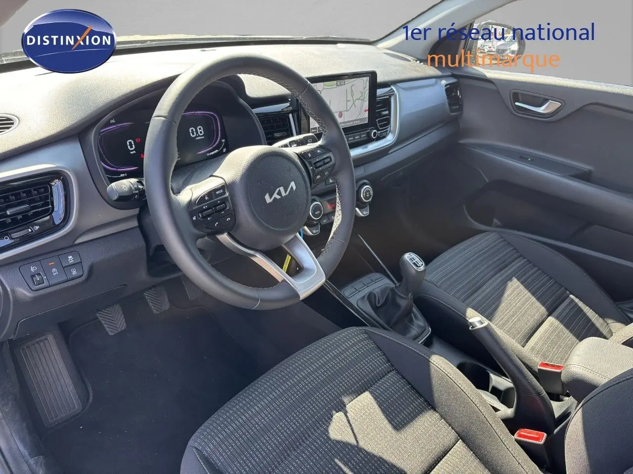 Vue intérieure côté conducteur du Kia Stonic 2024 avec volant multifonction, tableau de bord digital et sellerie tissu noire.