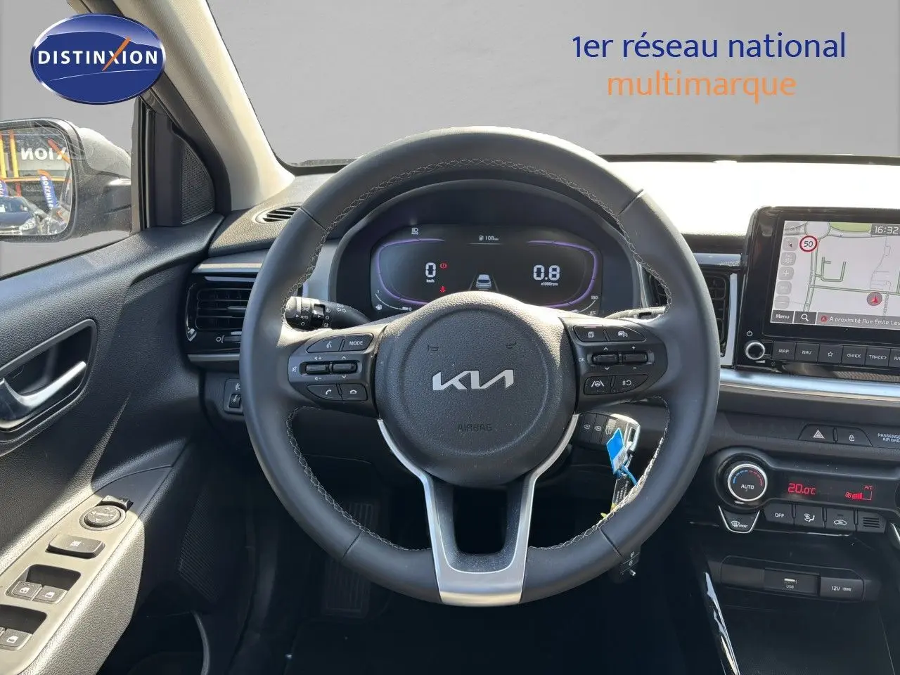 Vue intérieure centrée sur le volant du Kia Stonic gris météore 2024 avec tableau de bord numérique et écran GPS.