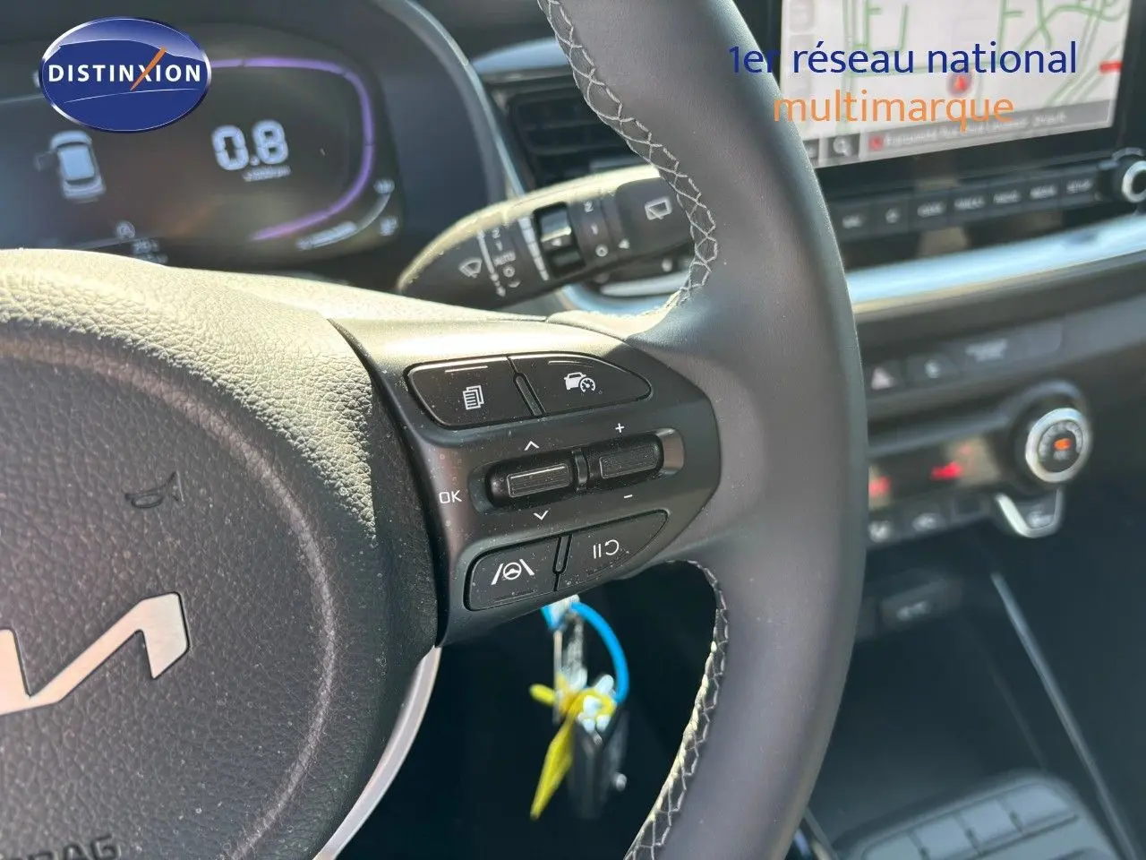 Gros plan sur le volant cuir avec commandes multifonctions du KIA STONIC gris météore 2024, tableau de bord numérique visible.