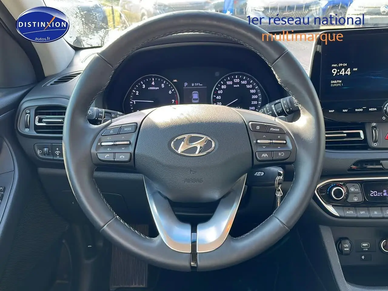 Vue frontale du volant cuir multifonction d'une Hyundai i30 gris argent 2024 avec tableau de bord et écran tactile.