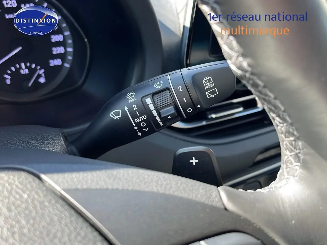 Gros plan sur la manette d'essuie-glace à gauche du volant cuir d'une Hyundai i30 gris argent 2024.