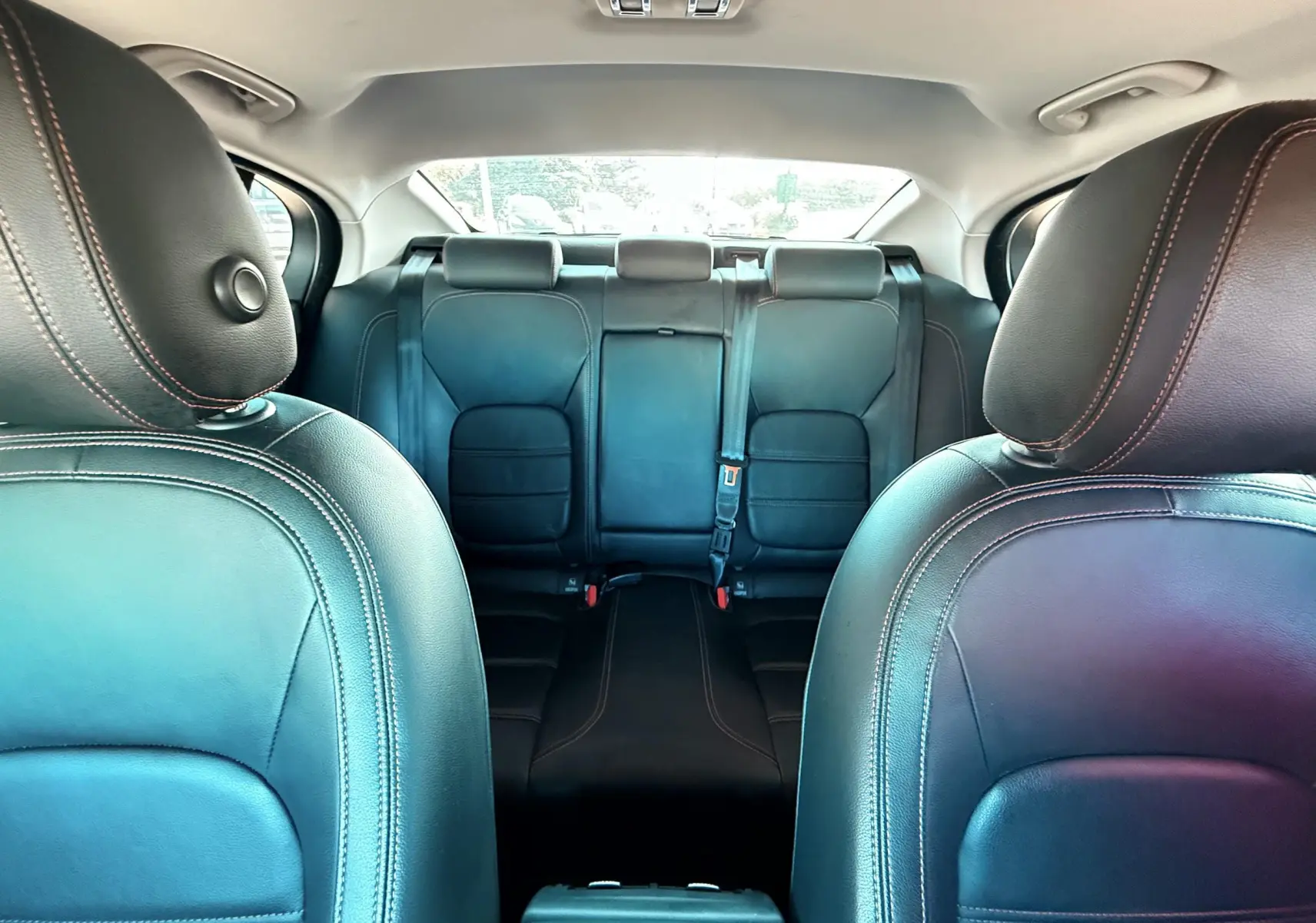 Vue intérieure montrant les sièges avant et arrière en cuir noir avec surpiqûres contrastantes d'une Jaguar XE 2019.