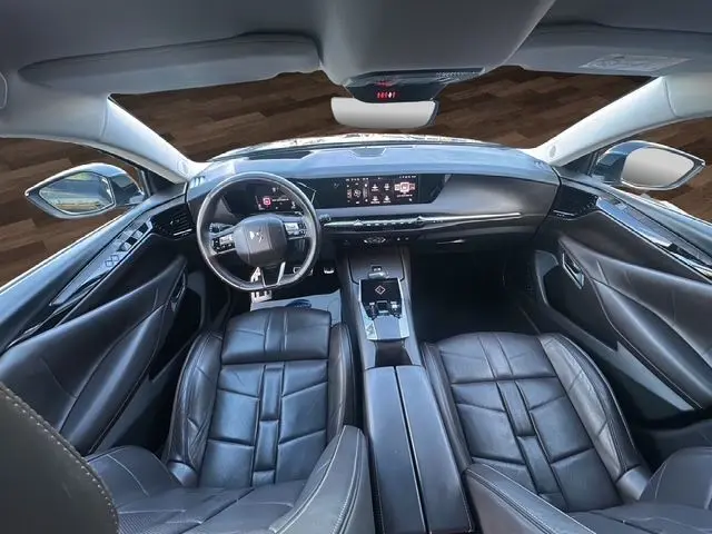 Vue intérieure avant du DS4 2022 noir, avec tableau de bord numérique, volant multifonction et sièges cuir noir.