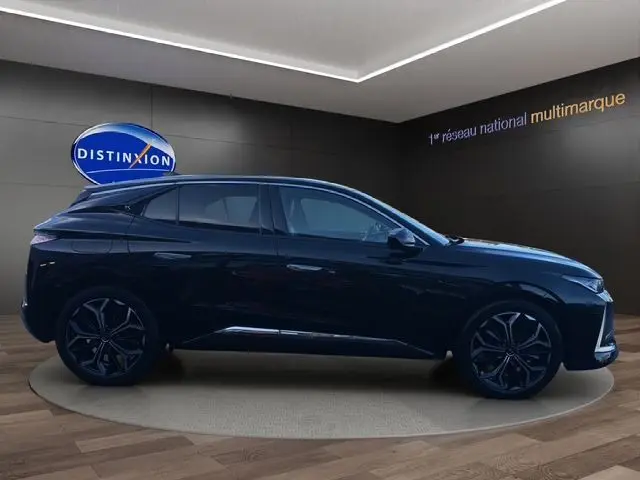 Profil côté gauche d'une DS4 noire 2022 dans un showroom, soulignant ses jantes noires et lignes élégantes.