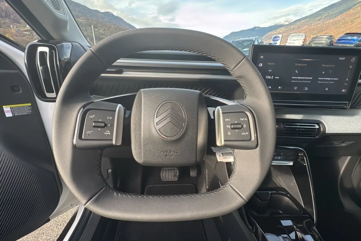 Vue intérieure centrée sur le volant cuir multifonctions du Citroën C3 Aircross blanc banquise avec écran tactile 10,25 pouces.
