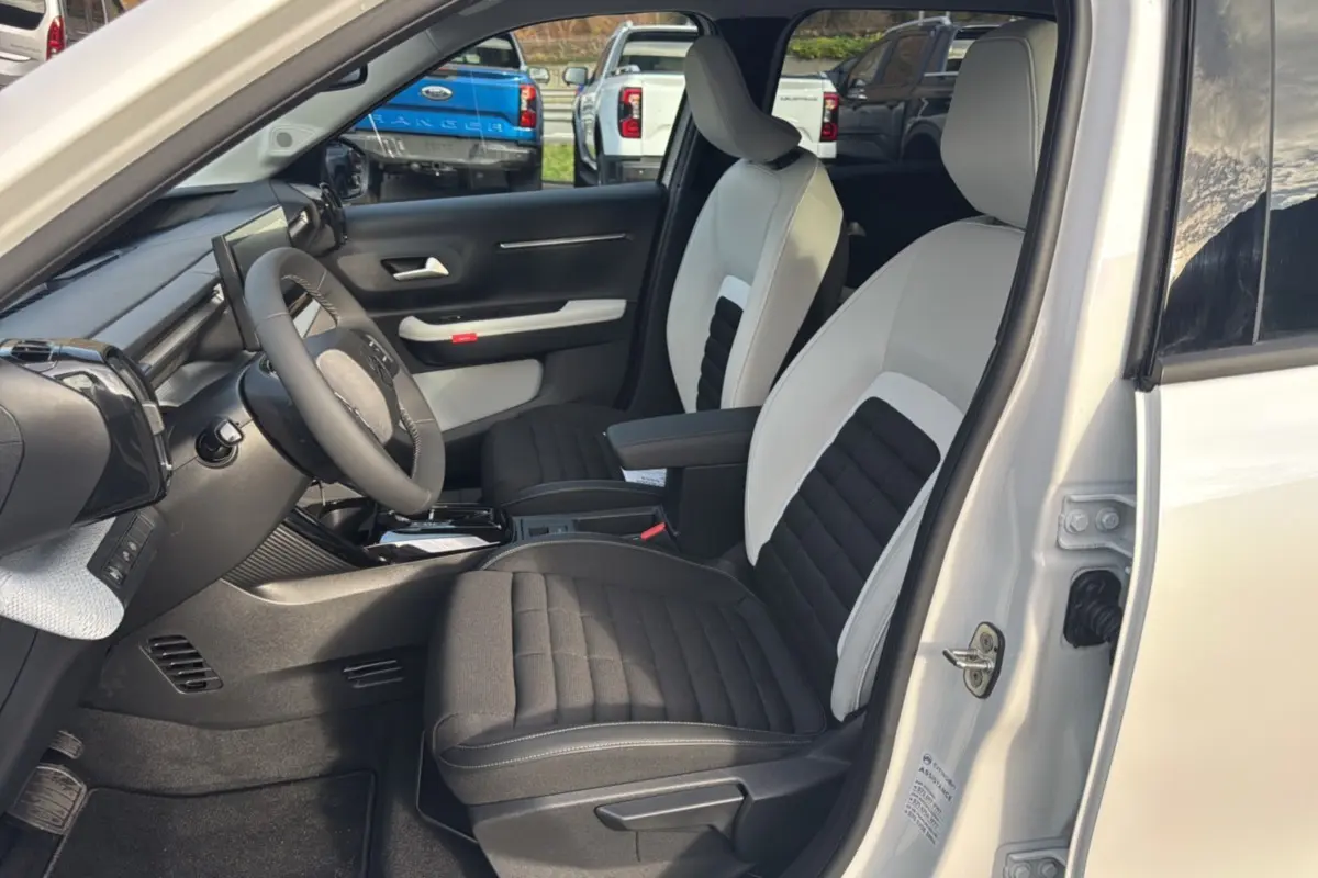 Vue intérieure côté conducteur du Citroën C3 Aircross blanc banquise, sièges tissu bicolores avec accoudoir central.