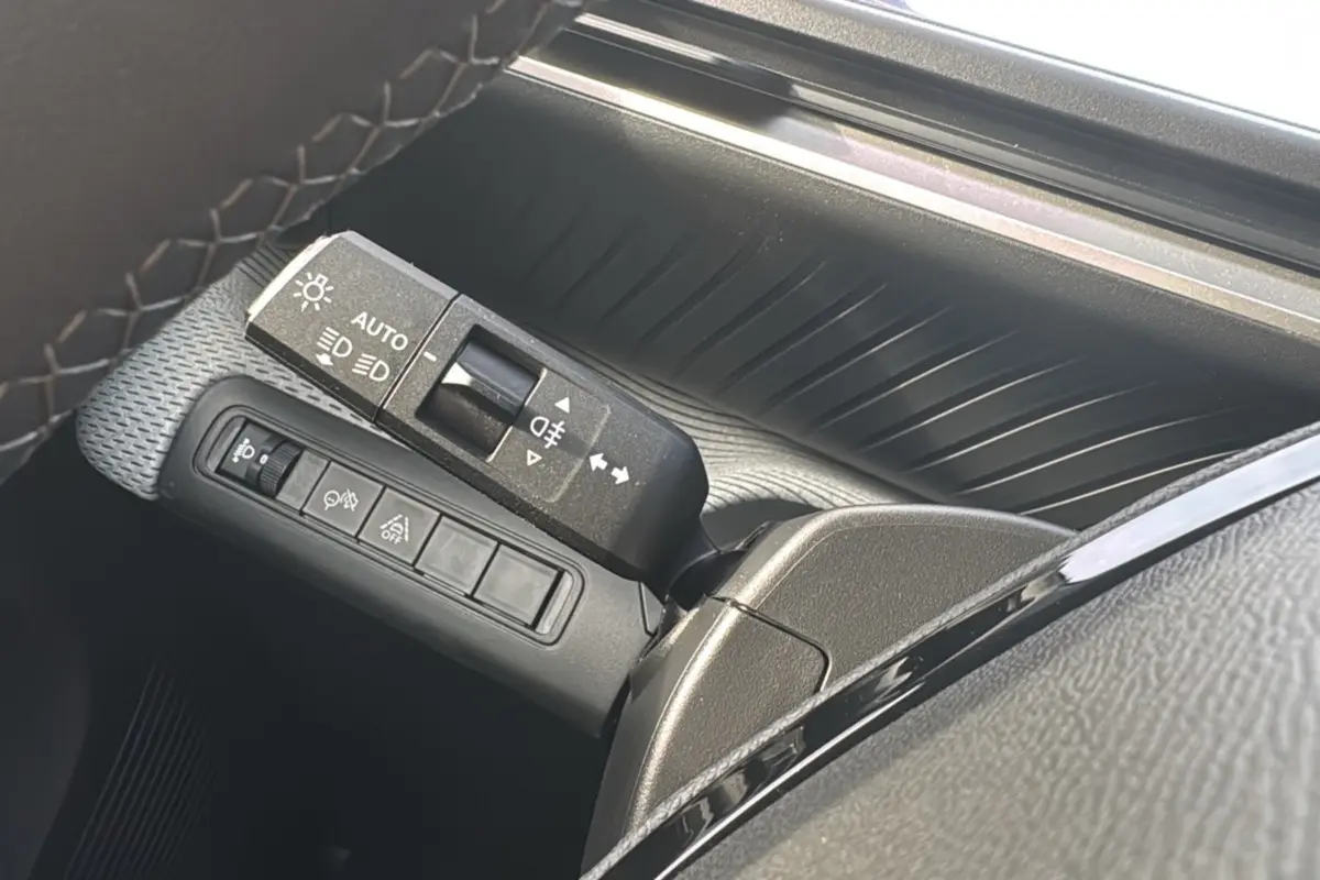 Gros plan sur la commande des feux et clignotants côté gauche du volant d'une Citroën C3 Aircross blanc banquise.