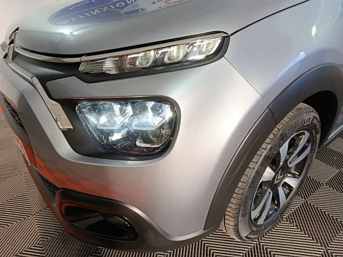 Gros plan sur l'avant droit gris foncé du Citroën C3 2024, mettant en valeur ses phares LED et sa roue avec jante noire.