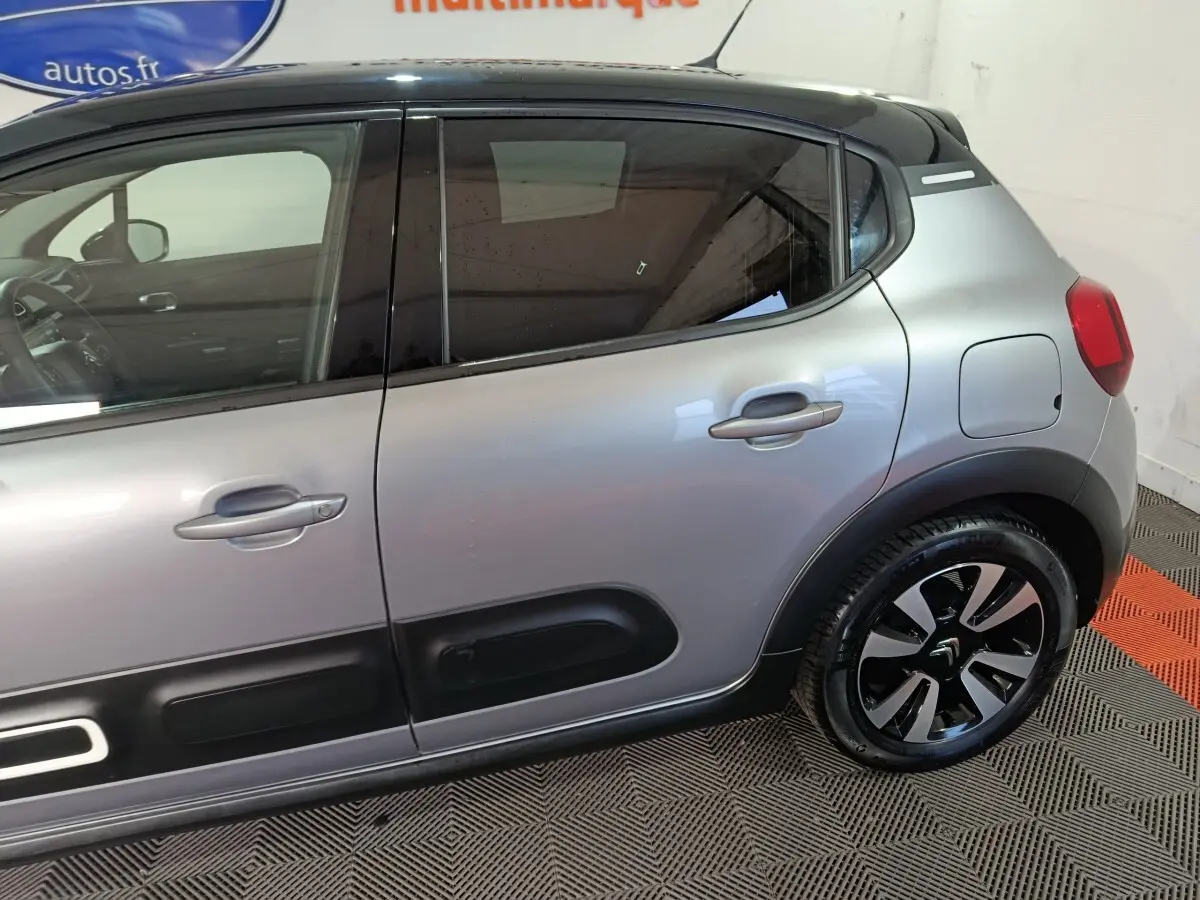 Vue latérale droite d'une Citroën C3 gris foncé avec protections de porte noires et jantes distinctives.