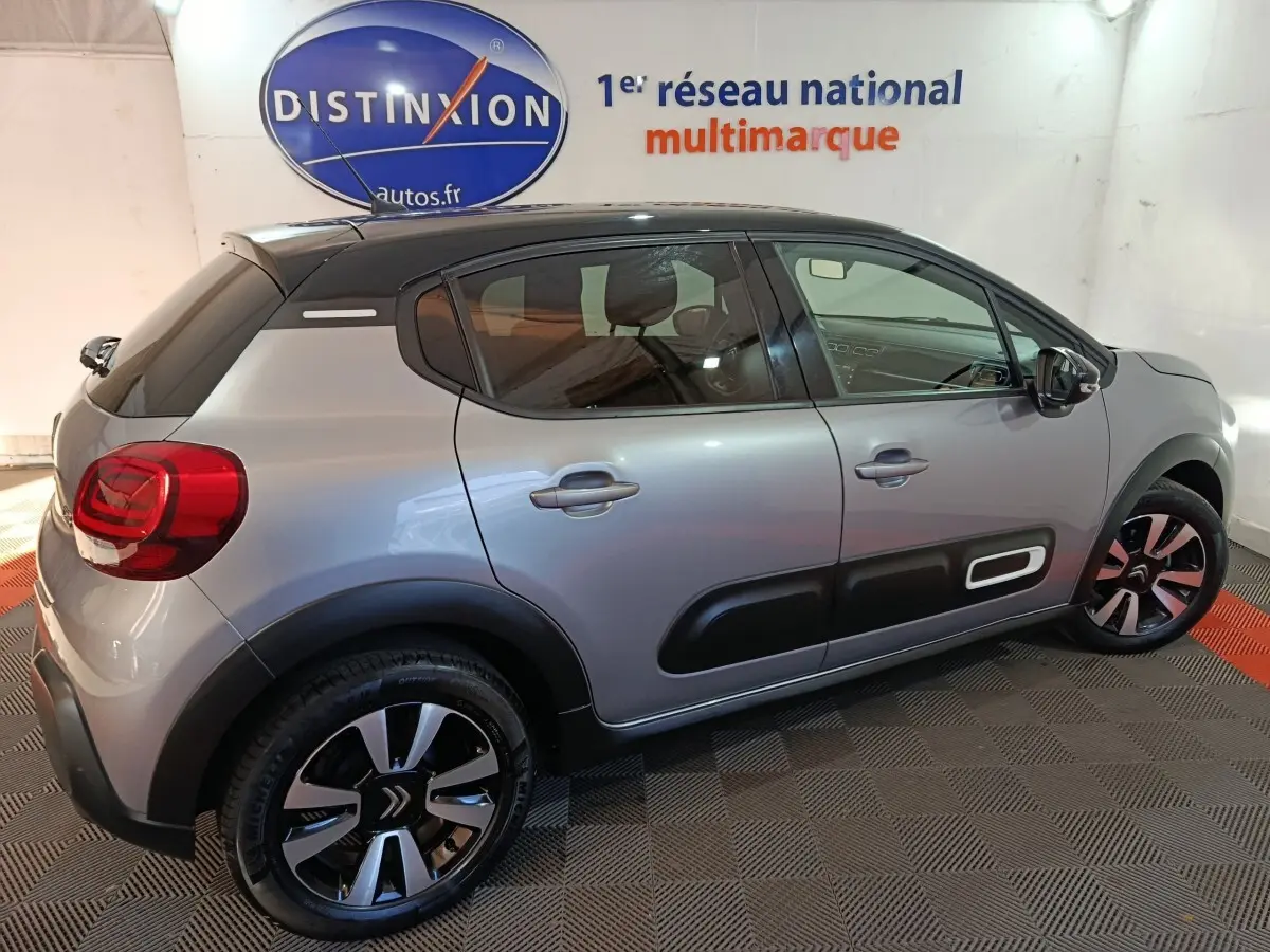 Vue côté droit arrière d'une Citroën C3 gris foncé avec protections latérales noires et jantes bicolores.