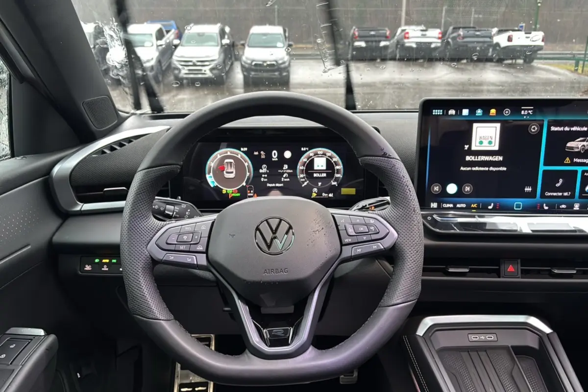Vue intérieure centrée sur le volant cuir multifonctions d’un Volkswagen T-Roc 2026 avec tableau de bord digital et écran tactile.