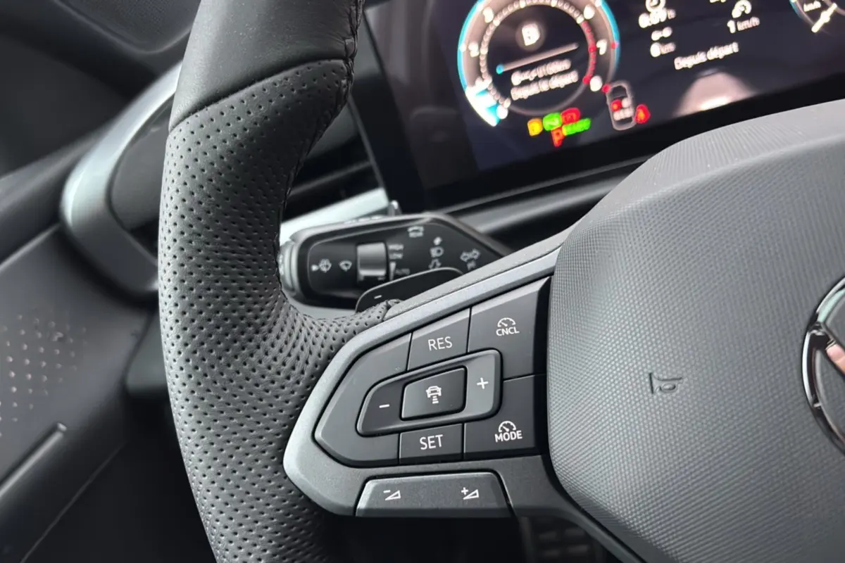 Gros plan sur le volant cuir noir perforé du Volkswagen T-Roc 2026 avec commandes multifonctions et tableau de bord digital.