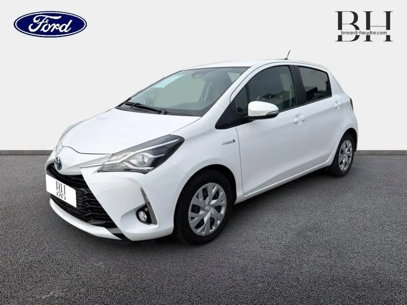 Toyota Yaris 116h blanc pur vue 3/4 avant droit avec phares et calandre distinctifs visibles.