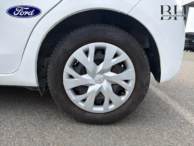 Gros plan sur la roue avant droite blanche d'une Toyota Yaris 116h avec enjoliveur distinctif en étoile.