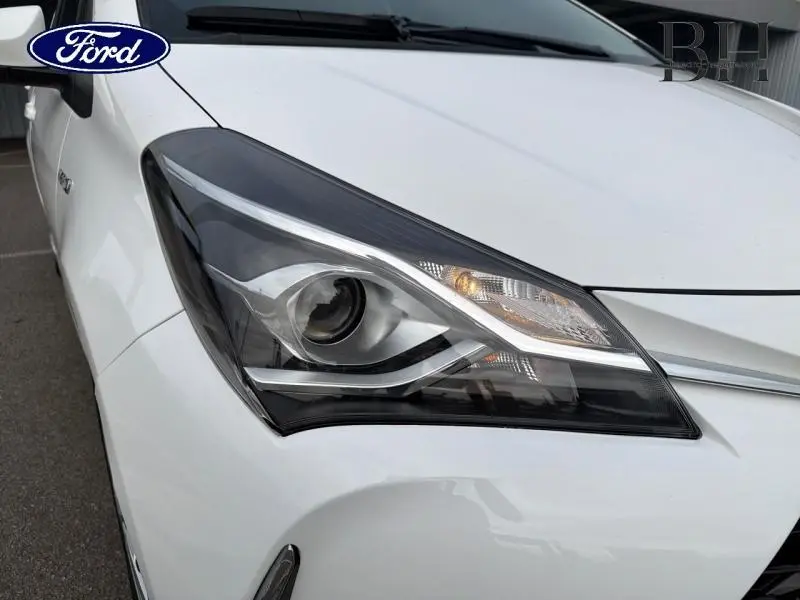 Gros plan sur le phare avant gauche d'une Toyota Yaris 116h blanche, soulignant ses lignes modernes et son éclairage LED.