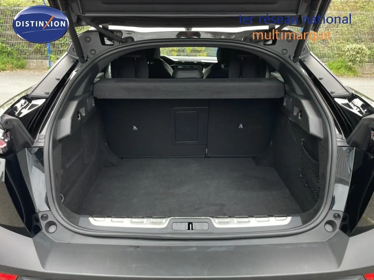 Coffre ouvert d’une Peugeot 408 Hybrid 145ch GT noir métal, vue arrière montrant l’espace de chargement vide.