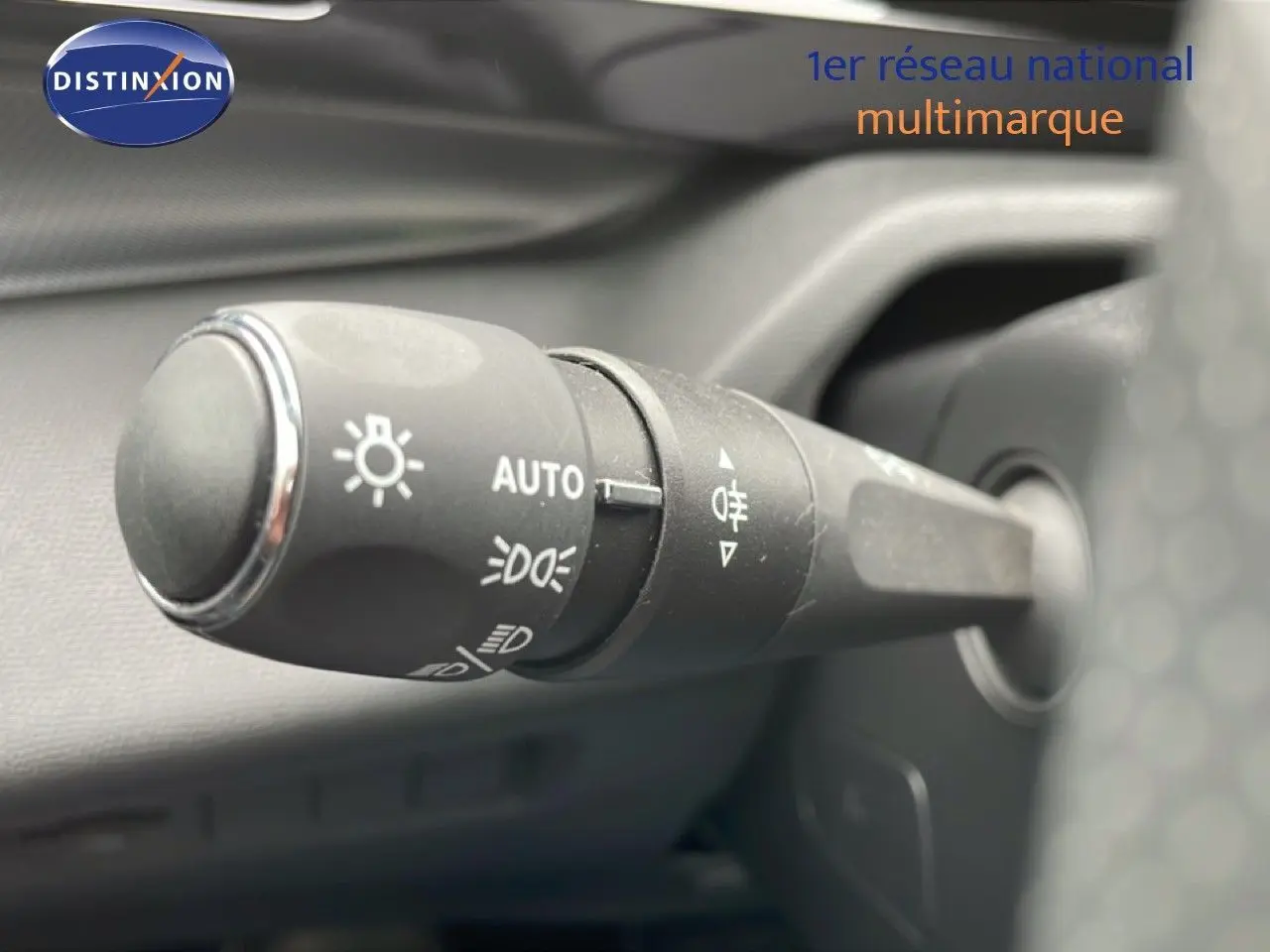 Gros plan sur la commande des feux automatique et antibrouillard dans l’habitacle du Peugeot 408 Hybrid 145ch noir métal 2024.
