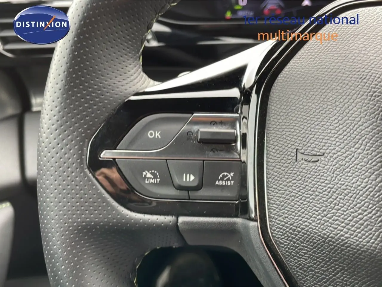 Gros plan sur les commandes gauche du volant noir perforé du Peugeot 408 Hybrid 145ch e-DCS6 GT 2024.