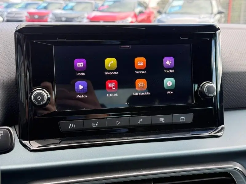 Écran tactile central du tableau de bord du SEAT Arona 2025 affichant les icônes radio, téléphone, véhicule et aides à la conduite.