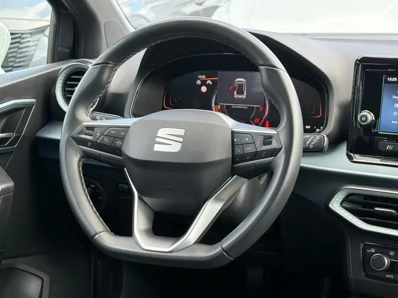 Vue rapprochée du volant multifonction noir du SEAT Arona 2025 avec tableau de bord numérique et écran central.