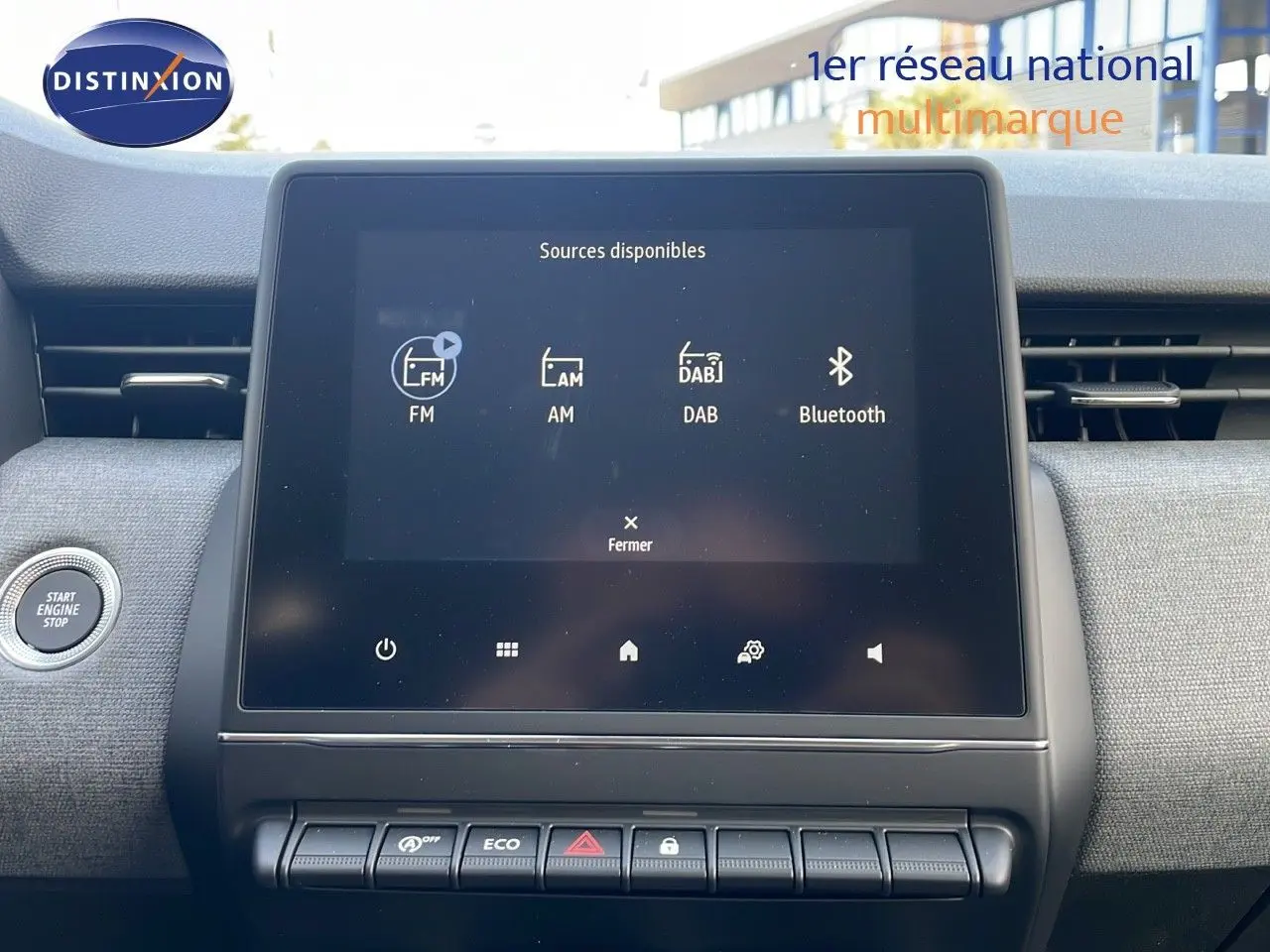 Écran tactile central affichant les sources audio dans l'habitacle d'une Renault Clio noire étoile métal, vue de face.