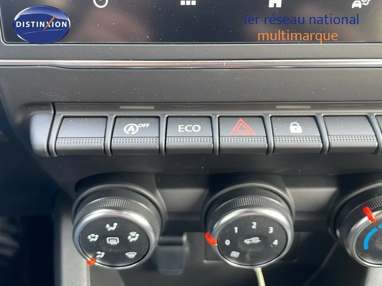 Gros plan sur les commandes de climatisation et boutons de fonction d'une Renault Clio noire étoile métal, intérieur avant.