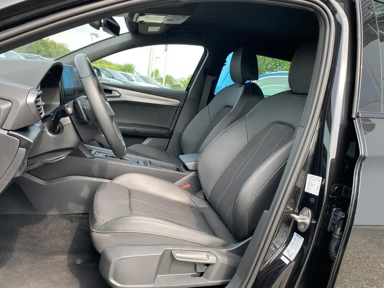 Intérieur côté conducteur de la CUPRA LEON ST 2024 noir Midnight avec sièges avant en cuir et tableau de bord moderne.