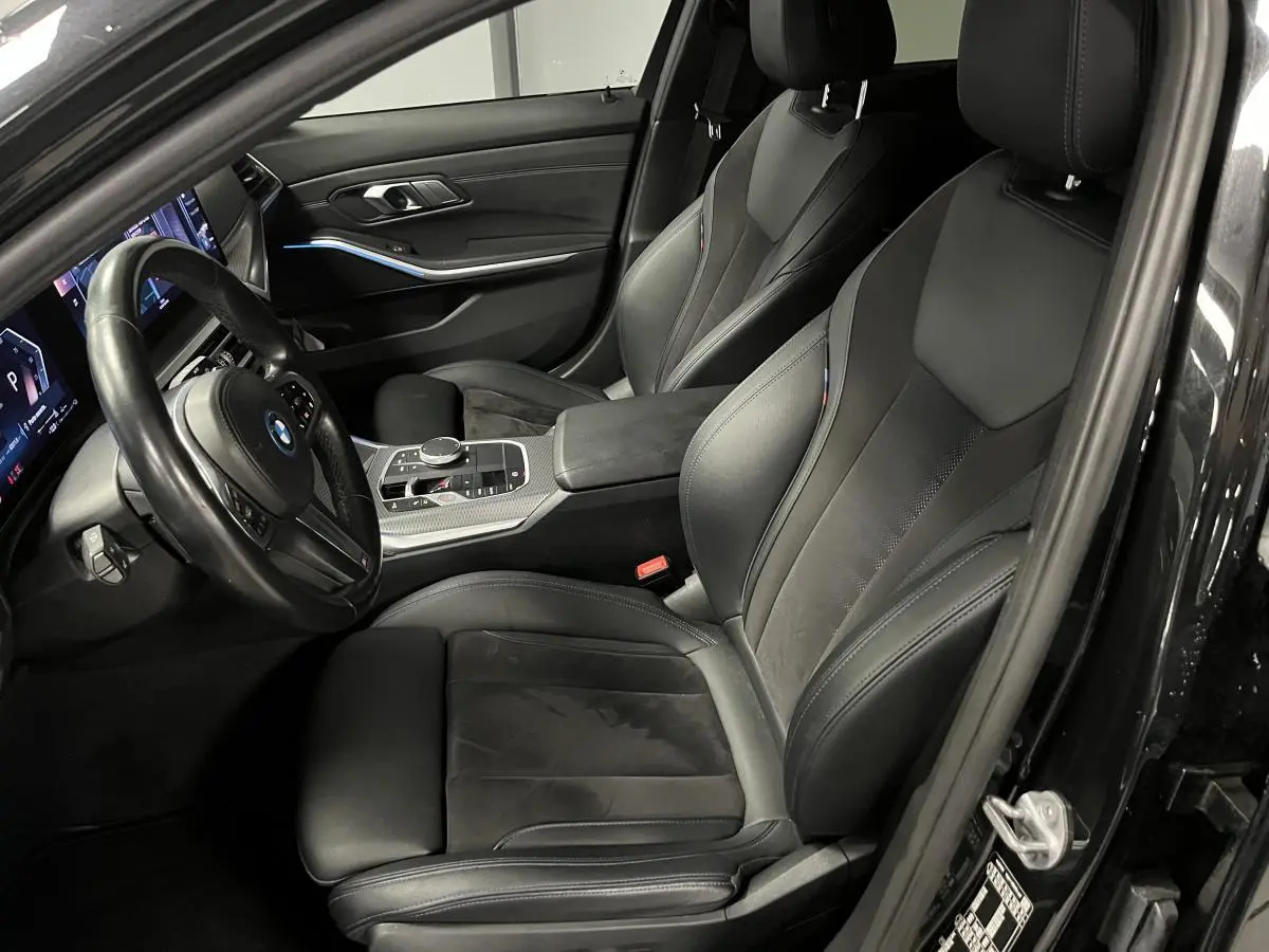 Intérieur avant droit de la BMW Série 3 320e Touring noir, sièges sport M en cuir et alcantara avec surpiqûres bleues.